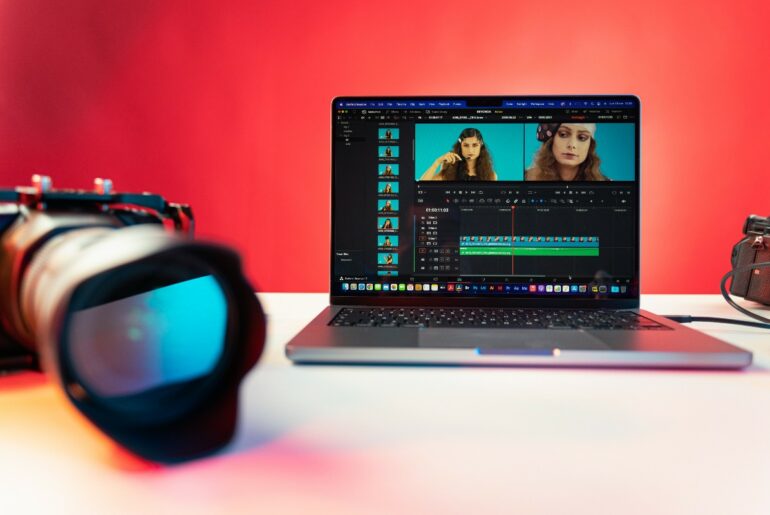 A camera beside a laptop displaying a video of a woman being edited