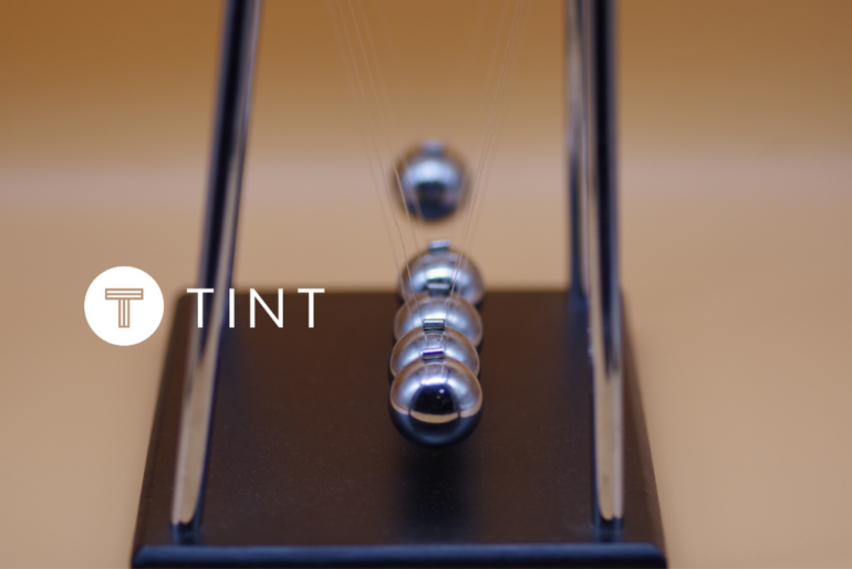 Marble Impact on Newton's Cradle next to TINT logo