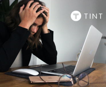 woman holding her head while working at laptop