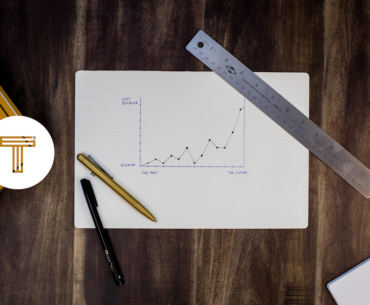 TINT logo next to graph paper featuring a chart on a wooden table